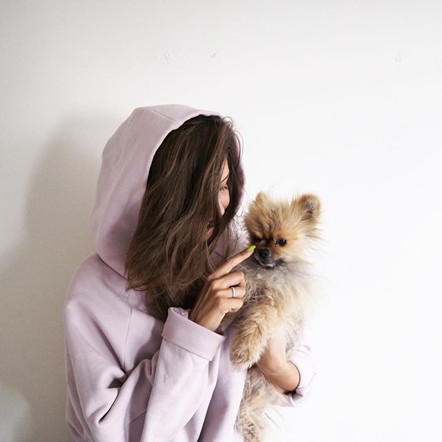 A woman carrying a Pomeranian while touching its nose