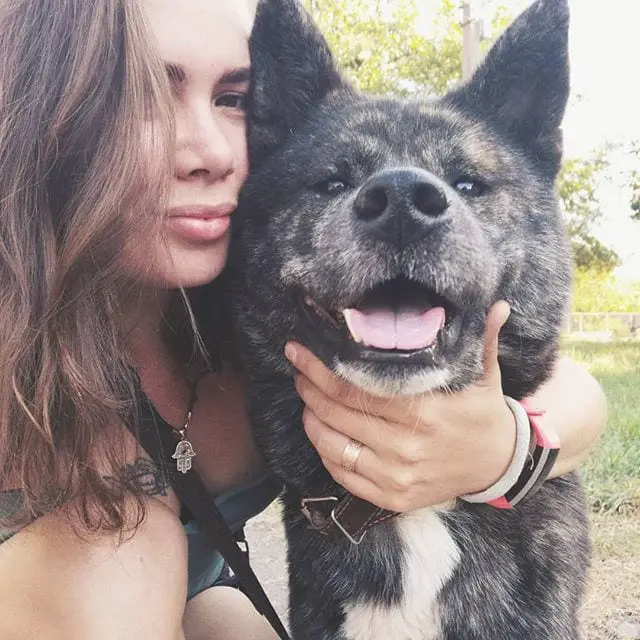 A woman taking a selfie while embracing her Akita