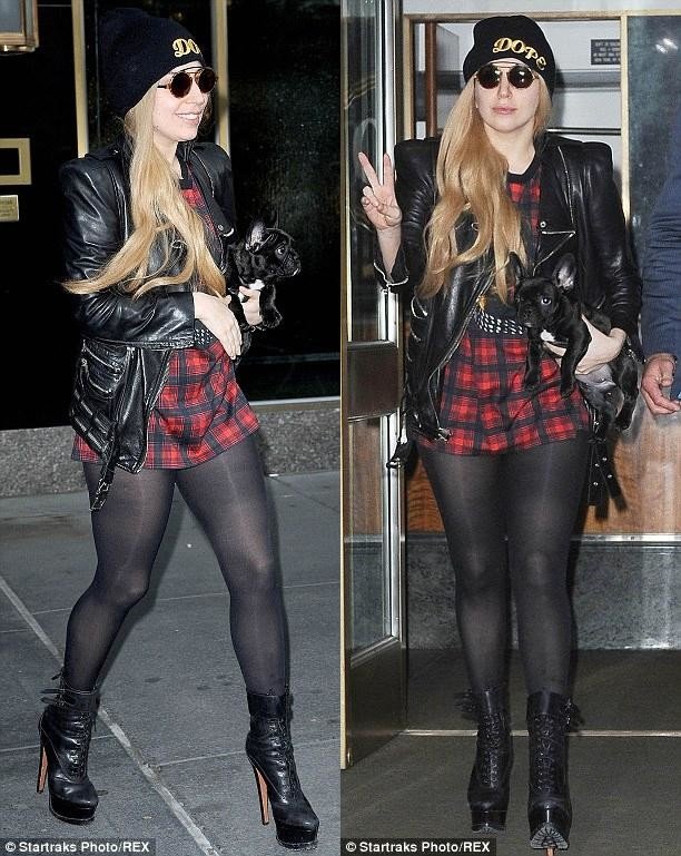 Lady Gaga walking in the street while holding her French Bulldog puppy