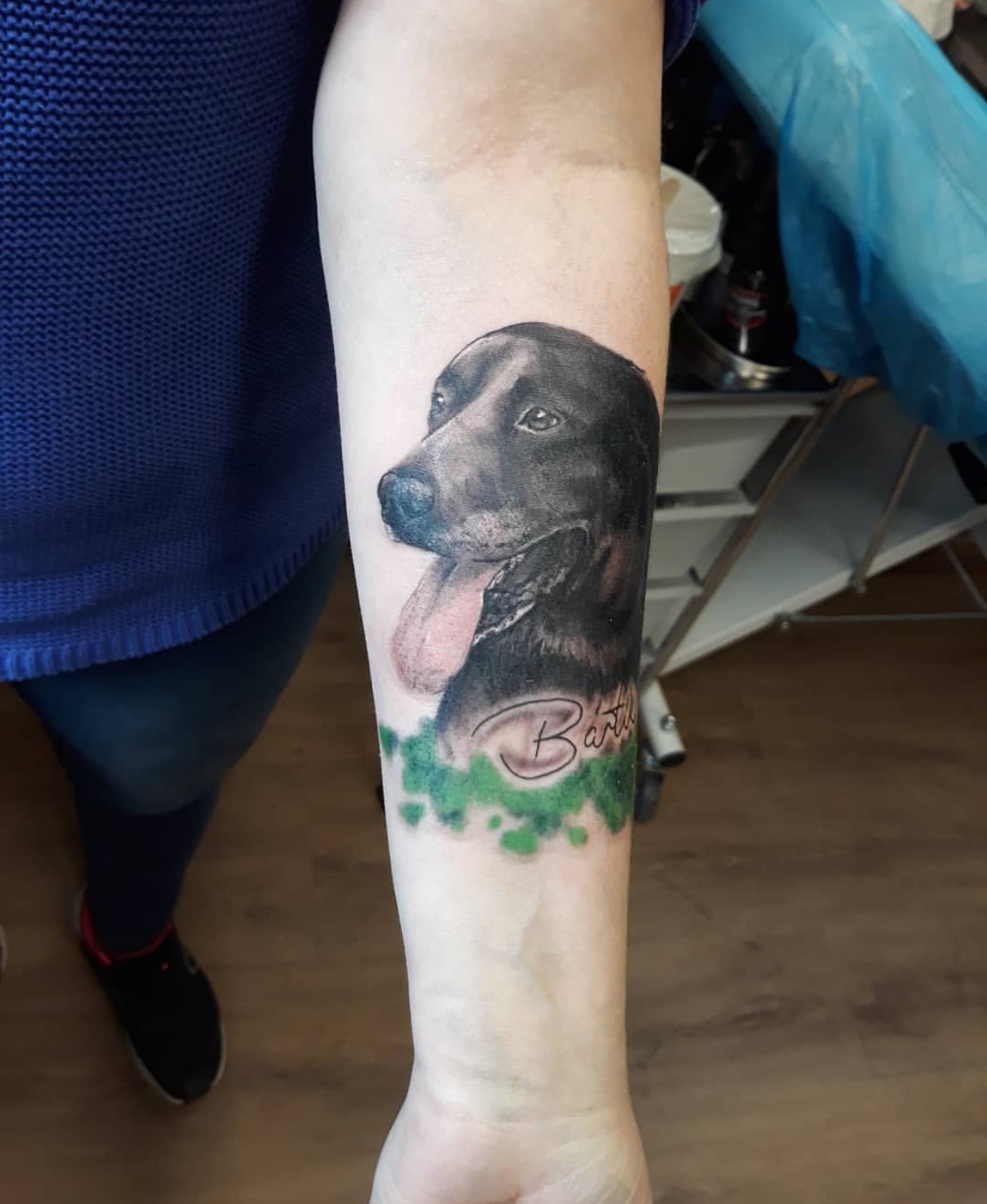 realistic black Labrador Retriever in the grass tattoo on the forearm