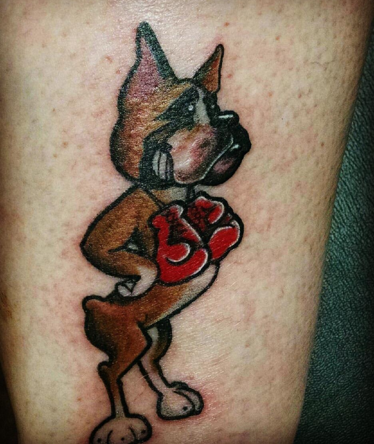 artwork of a Boxer with its paws on its waist and with a boxer gloves over its shoulder tattoo