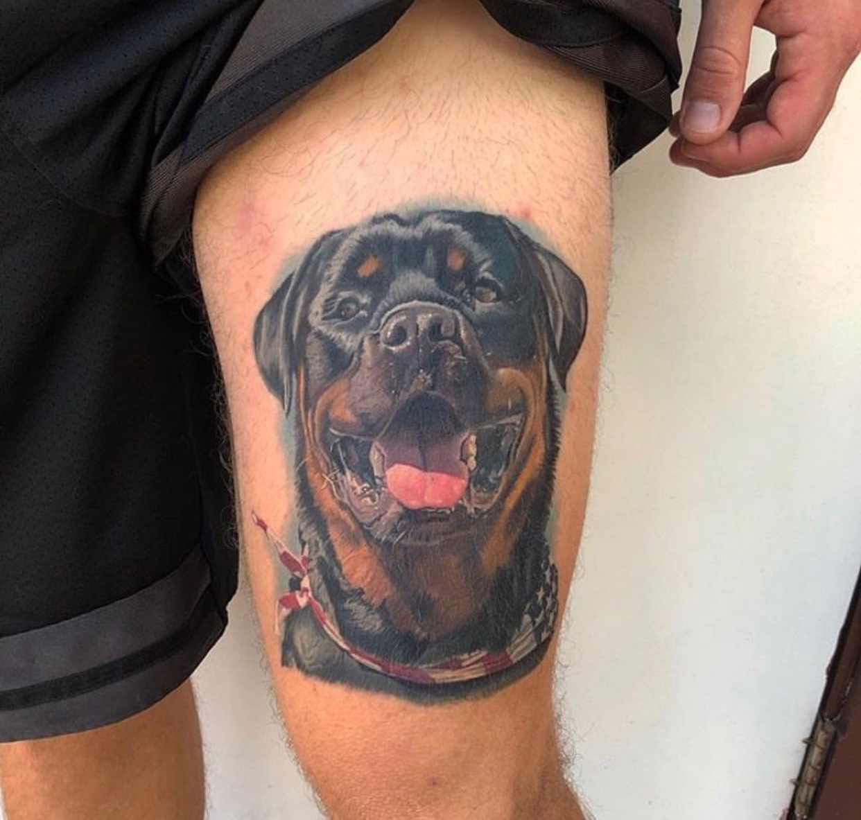 a happy face of a Rottweiler tattoo on thigh