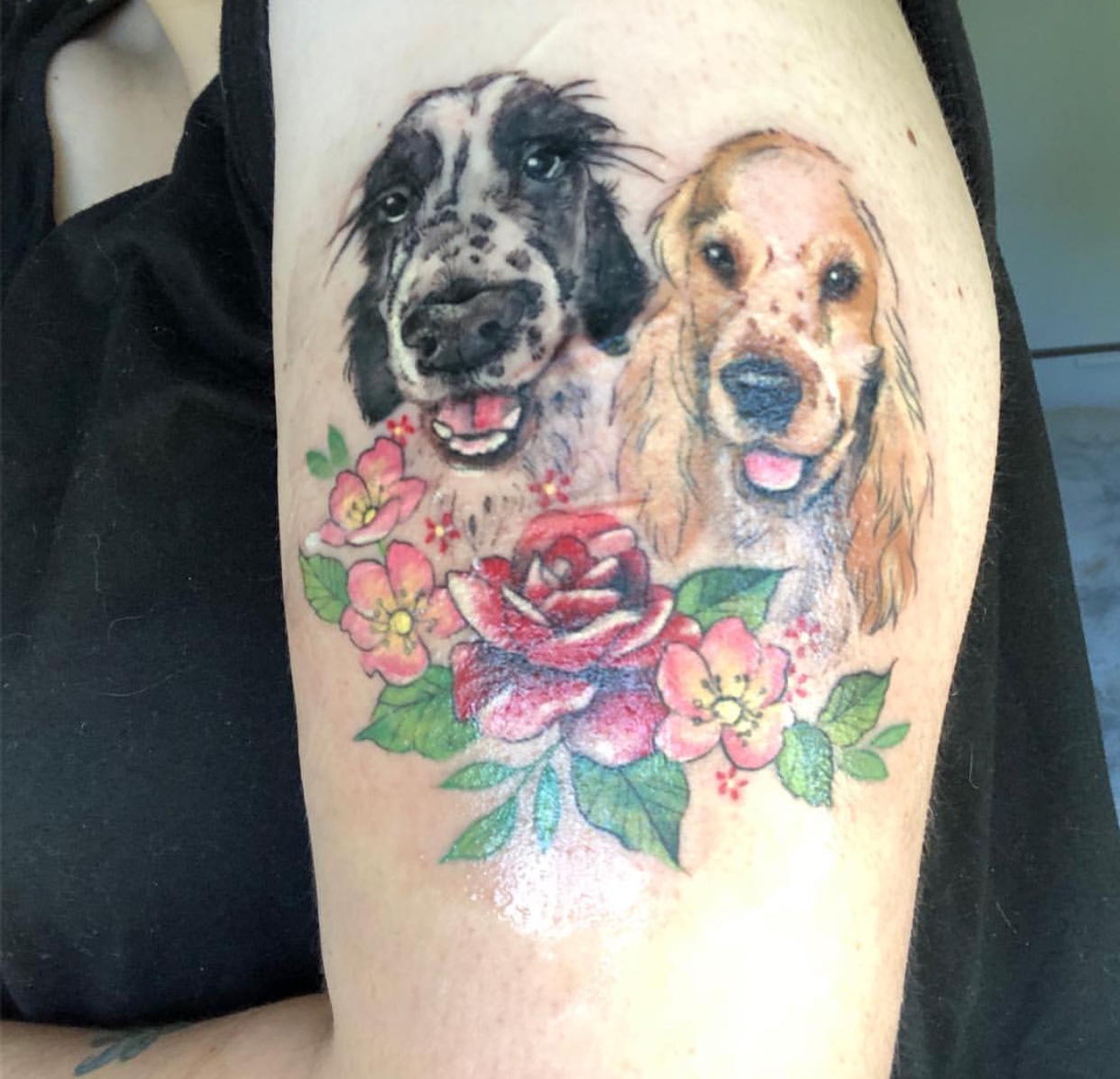 face of two smiling Cocker Spaniels with flowers and leaves tattoo on shoulder