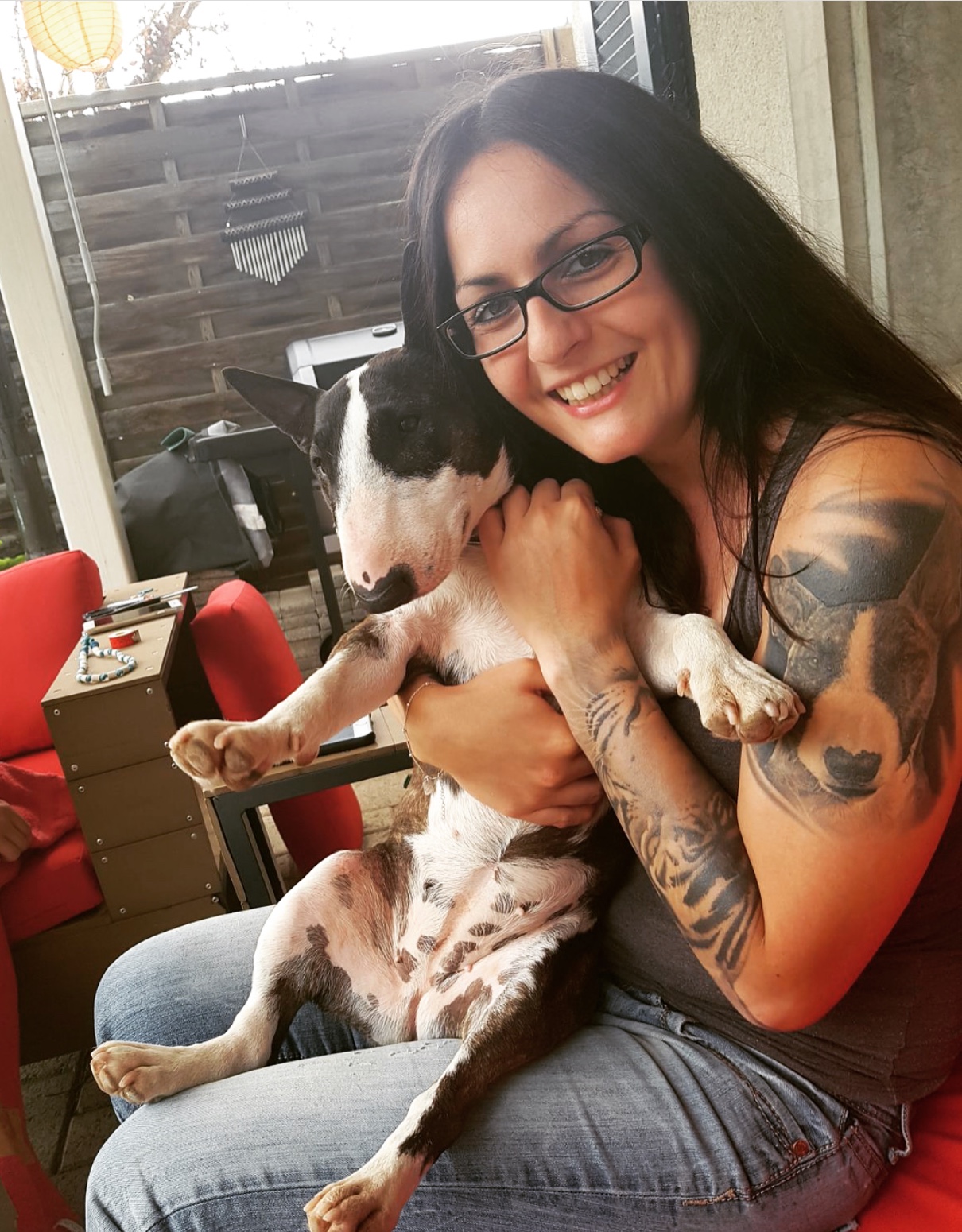 girl sitting with 3D Bull Terrier tattoo on its arms and a Bull Terrier on its lap