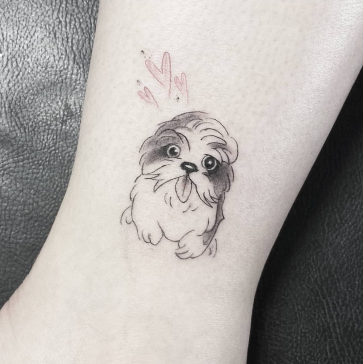 Shih Tzu sticking its tongue out with hearts above its head tattoo on the ankle