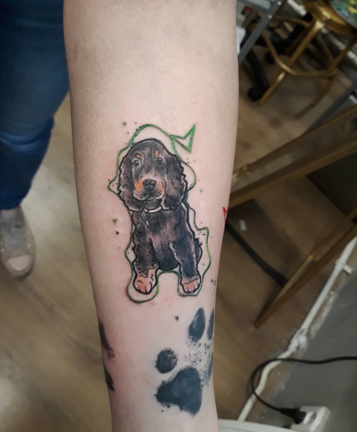 animated sitting Cocker Spaniel with a large paw print tattoo on the forearm