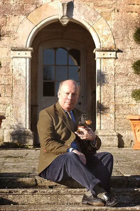 Julian Fellowes sitting on the stairs with his dachshund dog sitting on his lap