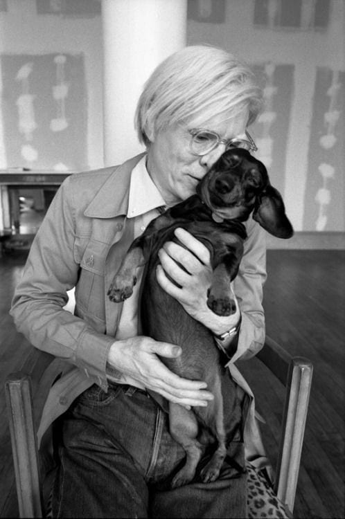 black and white photo of Andy Warhol kissing his dachshund dog