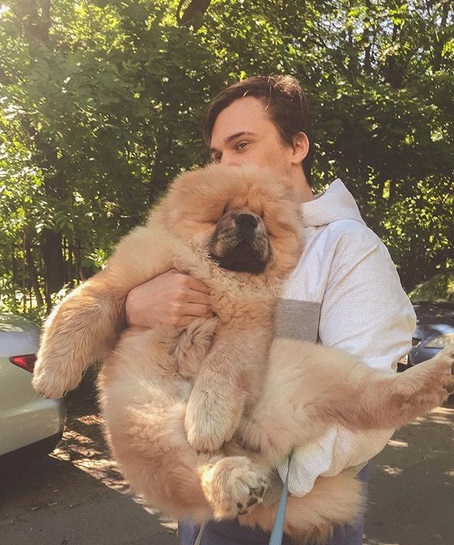A man carrying a Chow Chow puppy