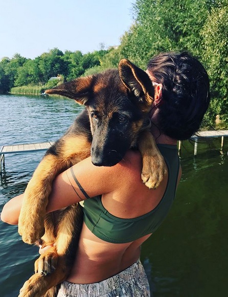 A woman carrying a German Shepherd puppy