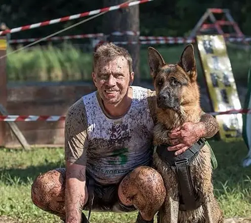 a man and a German Shepherd with dirt on their face and boy