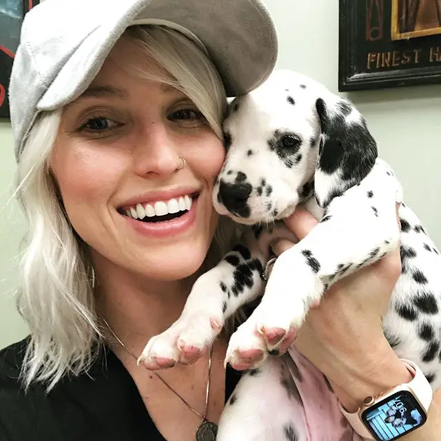 A woman taking a selfie while holding her Dalmatian puppy
