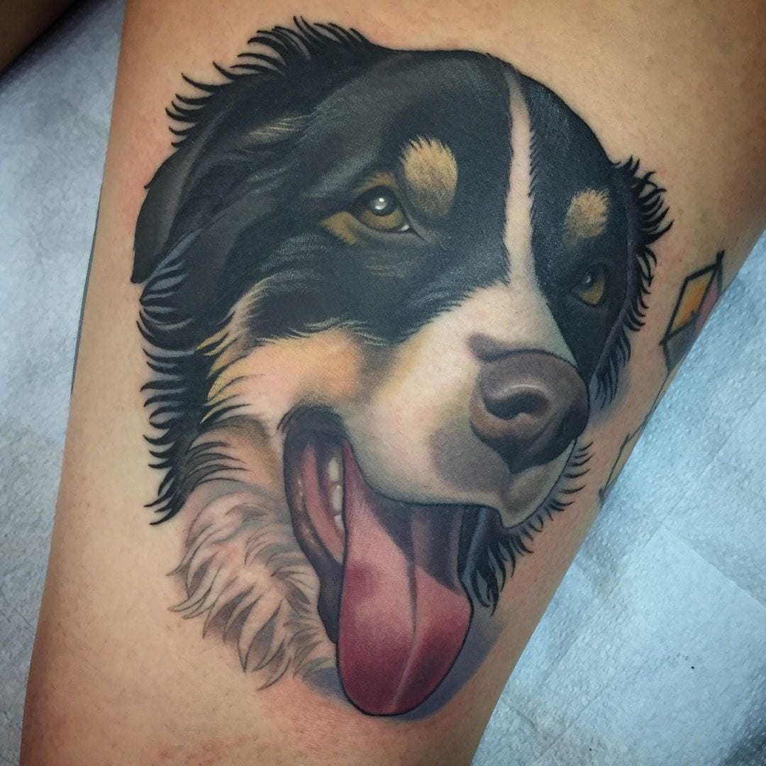 face of a Bernese Mountain Dog with its tongue out tattoo on the thigh