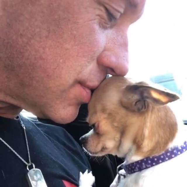 A man kissing the forehead of a Chihuahua