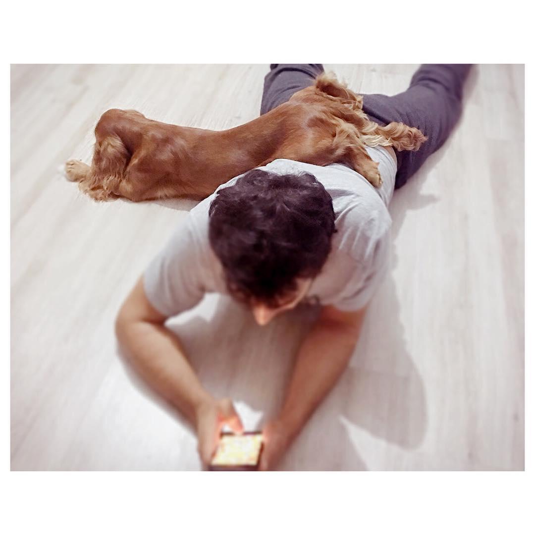 A man lying on the floor with the lower legs of a Cocker Spaniel on his back