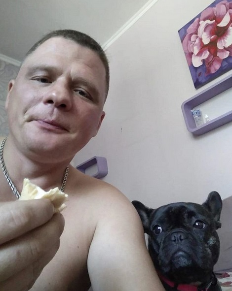 a man taking a selfie while holding a bread next to his French Bulldog staring at it next to him